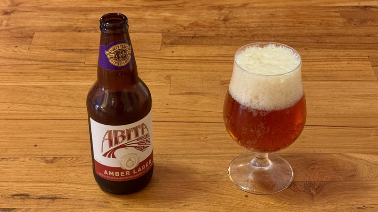 A bottle of Abita Amber Lager next to a beer glass filled with an amber beer.