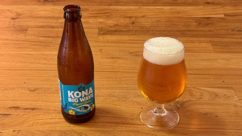 A bottle of Kona Big Wave next to a full beer glass.