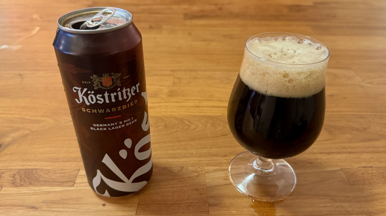 A tall brown can of Köstritzer Schwarzbier next to a beer glass filled with dark beer.