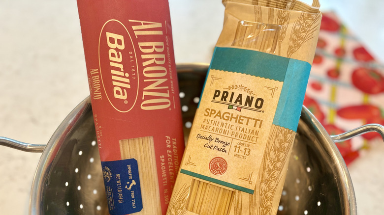 A colander with packs of Barilla Al Bronzo and Aldi Priano spaghetti