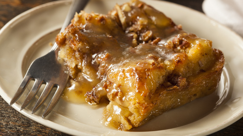 Bread pudding with sauce and fork on plate