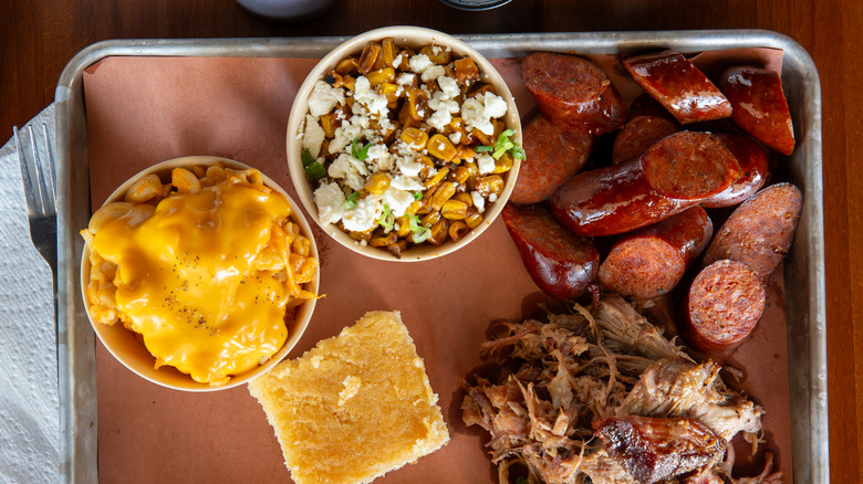 Sausage on barbecue plate with pulled pork, cornbread, and macaroni