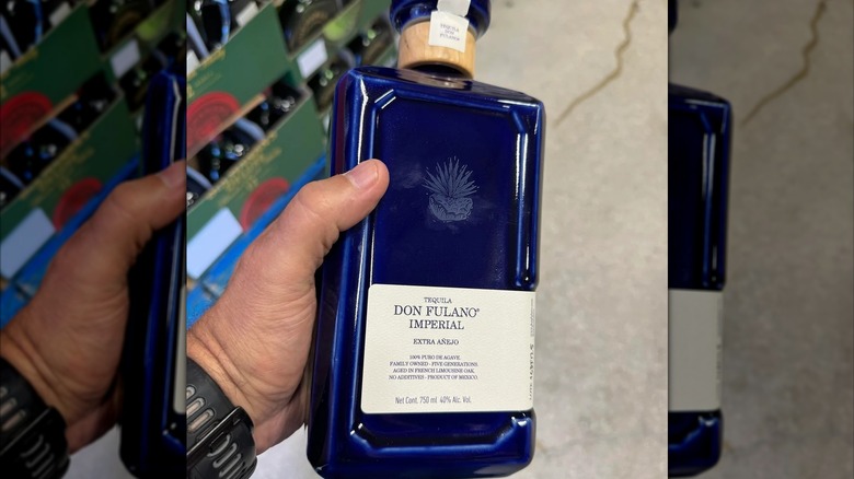 Customer holds bottle of Don Fulano Imperial tequila in Costco warehouse aisle
