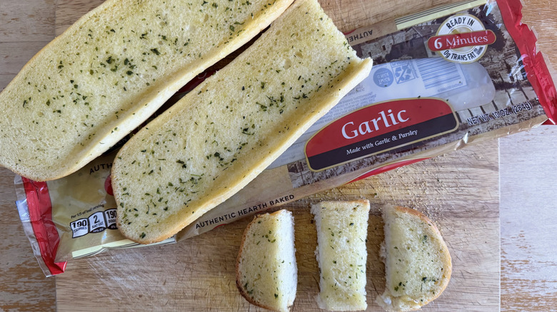 Two Aldi L'oven half garlic bread loaves on their bag above a few individual slices