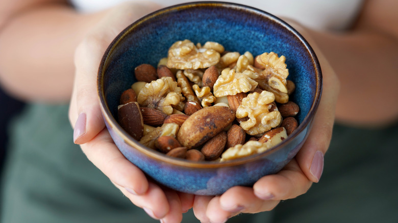 Hands holding a blue bowl full of nuts