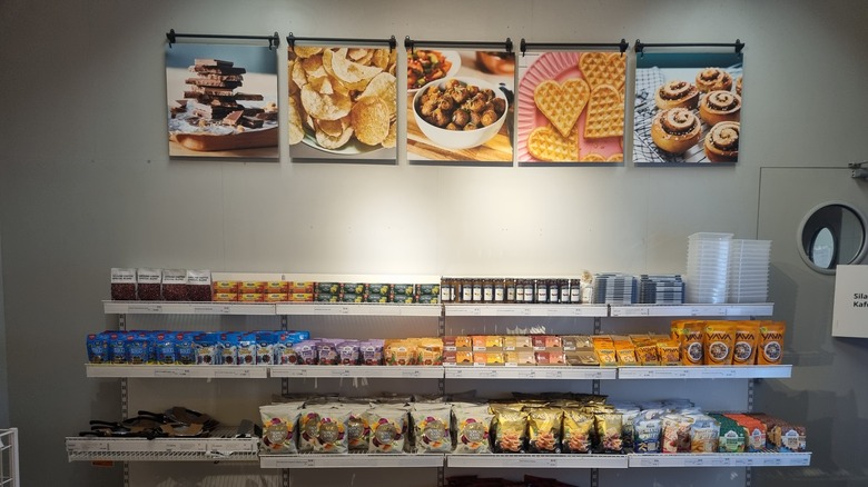 A neatly organized snack shelf in a store displaying a variety of chips, cookies, beverages, and packaged goods