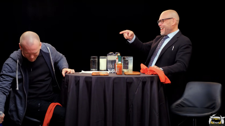 Alton Brown and Sean Evans celebrating the end of a "Hot Ones" episode