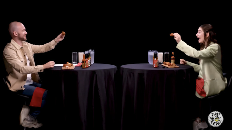 Sean Evans and Lorde cheersing their final wing on "Hot Ones"