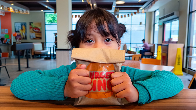 Little girl clutching Burger King bag inside Burger King restaurant
