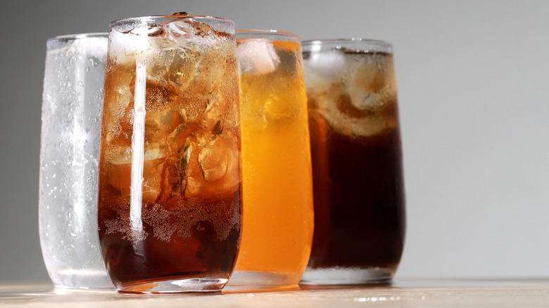 Assorted fizzy soft drinks in glasses with ice