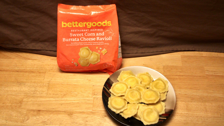 A cooked plate of Bettergoods brand Sweet Corn and Burrata Cheese Ravioli placed beside the bag it came in
