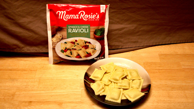 A cooked plate of Mama Rosie's brand Spinach & Cheese Ravioli placed beside the bag it came in