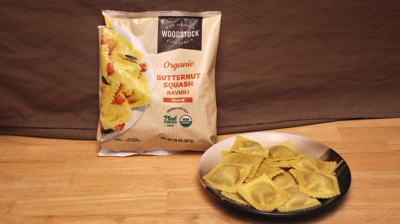 A cooked plate of Woodstock brand Vegan Butternut Squash Ravioli placed beside the bag it came in