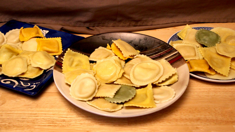Several plates sitting on a table and piled with a mix of different styles of ravioli