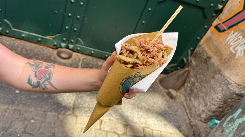 Arm with tattoo holding cuoppo, fried fish squid shrimp