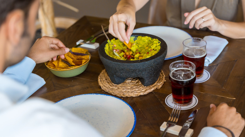 Couple eating guacamole out of bowl at restaurant