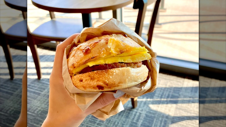 Hand holding asiago sausage and egg sandwich