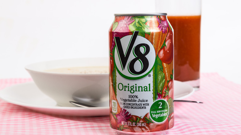 V8 Original Vegetable Juice can on table with red checkered tablecloth and bowl of soup and drink