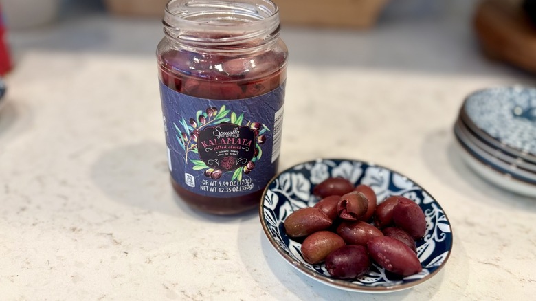 An open jar and bowl of Aldi Specially Selected Kalamata pitted olives