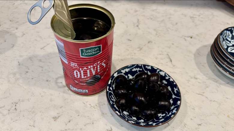 An open can and bowl of Aldi Tuscan Garden black olives