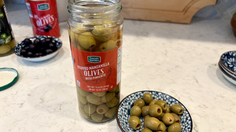 An open jar and bowl of Aldi Tuscan Garden brand Manzanilla olives with pimiento