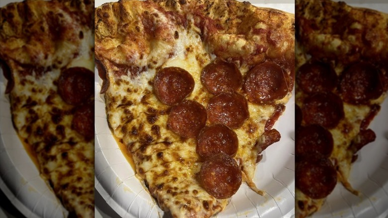 A greasy slice of pepperoni pizza from Costco's food court on a paper plate