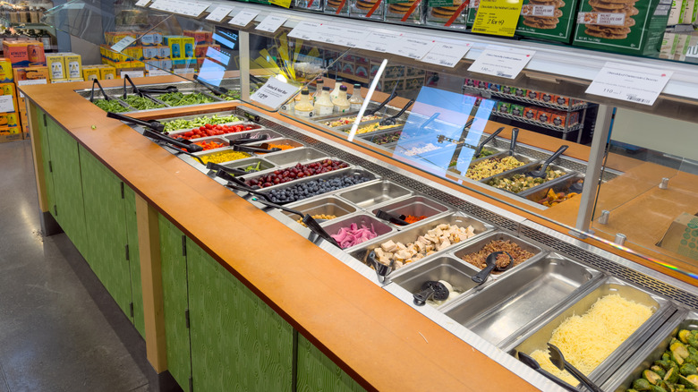 Salad bar filled with bins of fresh vegetables and toppings