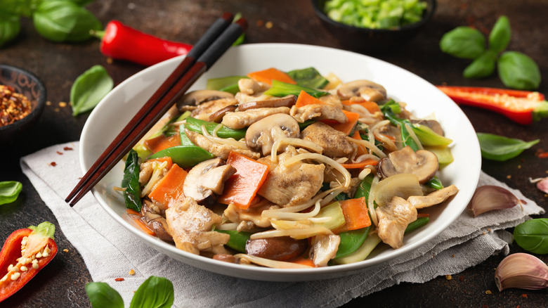 Chop suey on white plate with chopsticks