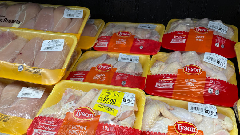 packages of raw chicken in grocery store refrigerator