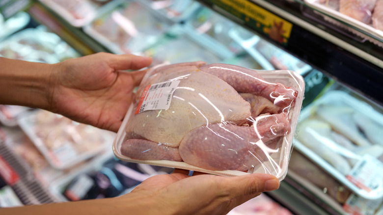 hands holding package of raw chicken