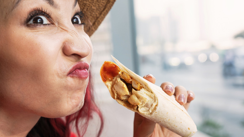 Woman making bad face holding chicken wrap