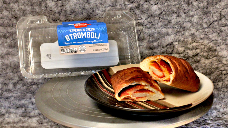 A Mama Cozzi's Pepperoni & Cheese Stromboli on a plate beside its plastic container