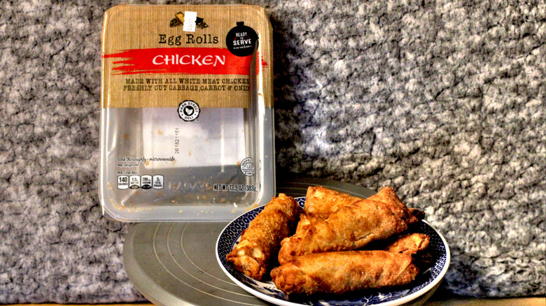 A plate of Park Street Deli chicken egg rolls beside the plastic container they came in