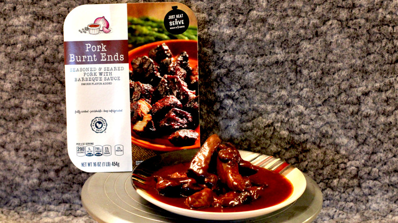A plate of Park Street Deli Pork Burnt Ends in sauce beside the container they came in