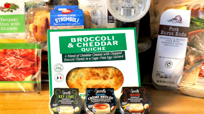A close up of a selection of the prepared foods from Aldi's house brands, including broccoli and cheddar quiche and Specially Selected parfait desserts