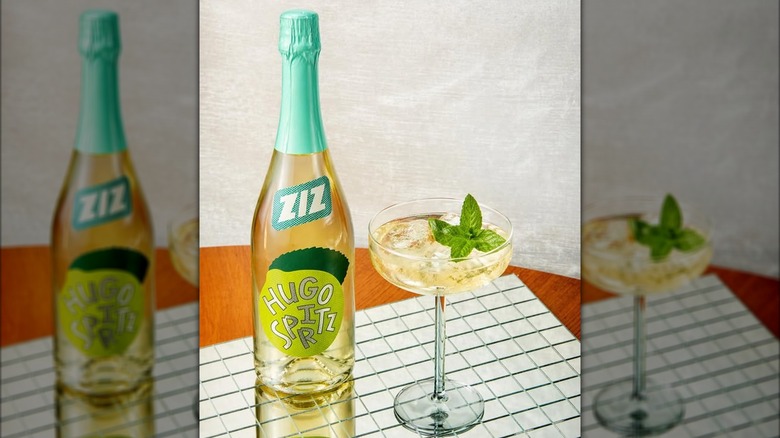 A bottle of Ziz Hugo Sparkling Spritz beside a glass with the beverage in it.