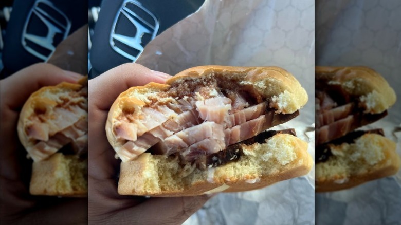 Someone holding a Buc-ee's Turkey BBQ Sandwich with a few bites taken out of it.