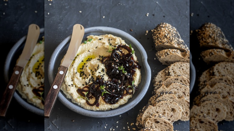 Hummus with caramelized onions, spreading knife, and bread