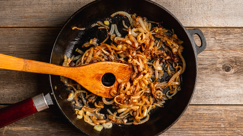 Skillet full of caramelized onions with wooden spoon