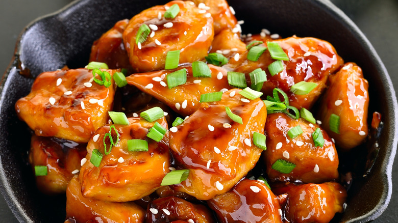 teriyaki chicken served in cast iron pan with sesame seeds and chive garnish