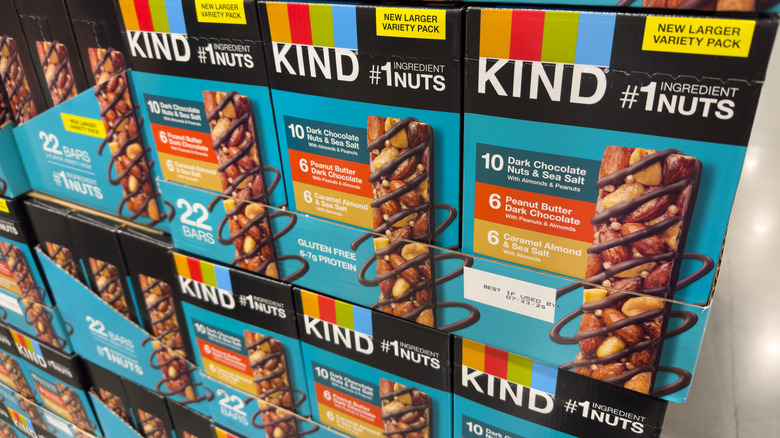 Several boxes of Kind Nut bars stacked up at the grocery store.