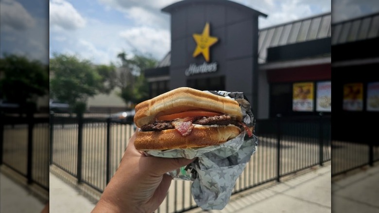 A hand holding a Hardee's Frisco Breakfast Burger.