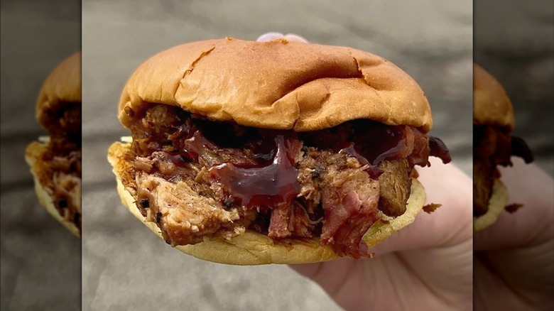 A hand holding Arby's Quarter Pound Chopped Brisket Sandwich.