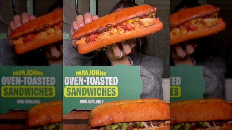 Papa John's Oven-Toasted Sandwiches held up by a person next to a Papa John's box