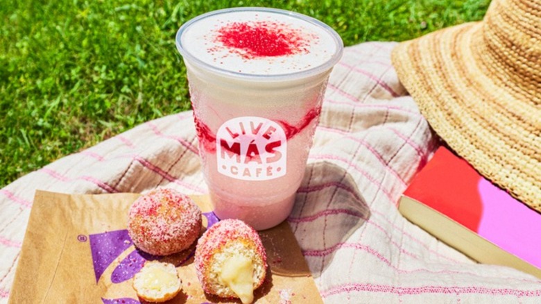 Taco Bell's Strawberry Cinnabon Delights on a blanket next to a drink and a straw hat