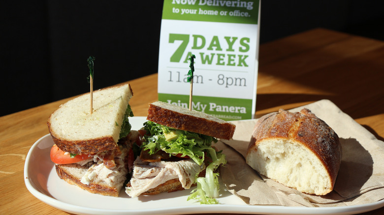 A Panera Bread sandwich on a table with a sign behind