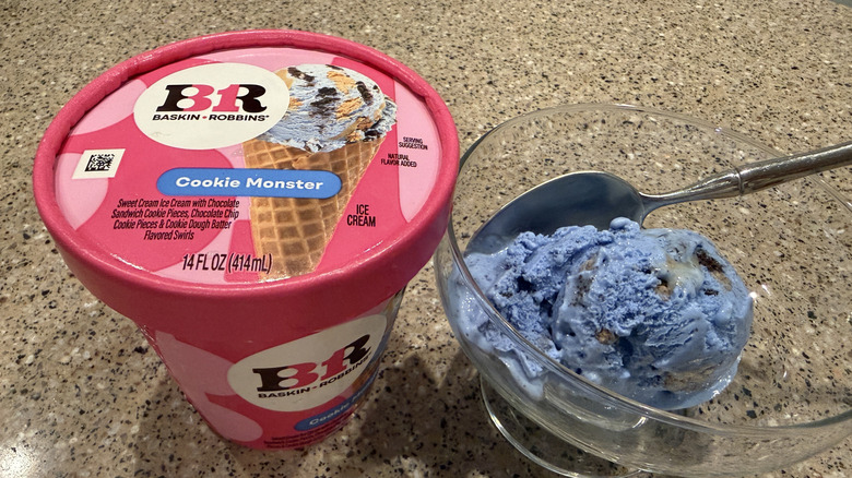 Baskin Robbins pint of Cookie Monster with a scoop in a glass bowl with a spoon