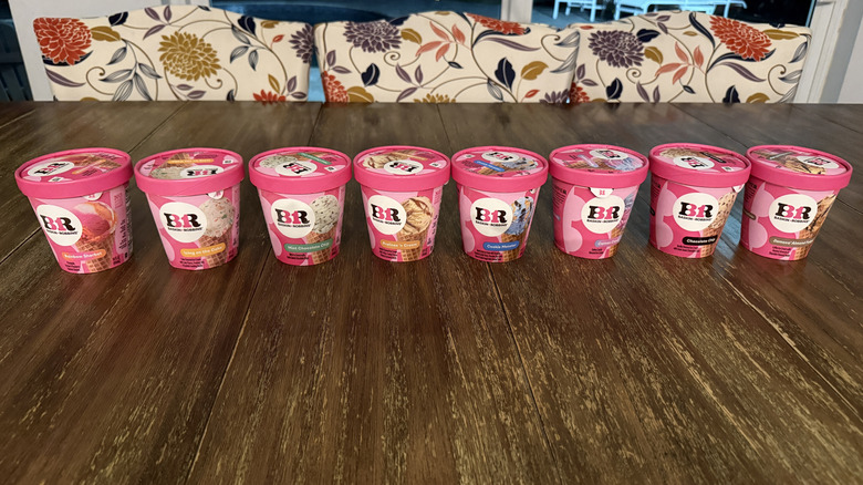Eight flavors of Baskin Robbins ice cream on a wooden table