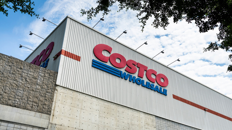 The Costco Wholesale sign with lights above it on the side of a Costco warehouse.