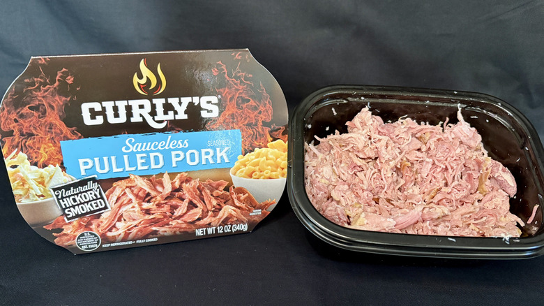 pulled pork in black container next to Curly's packaging